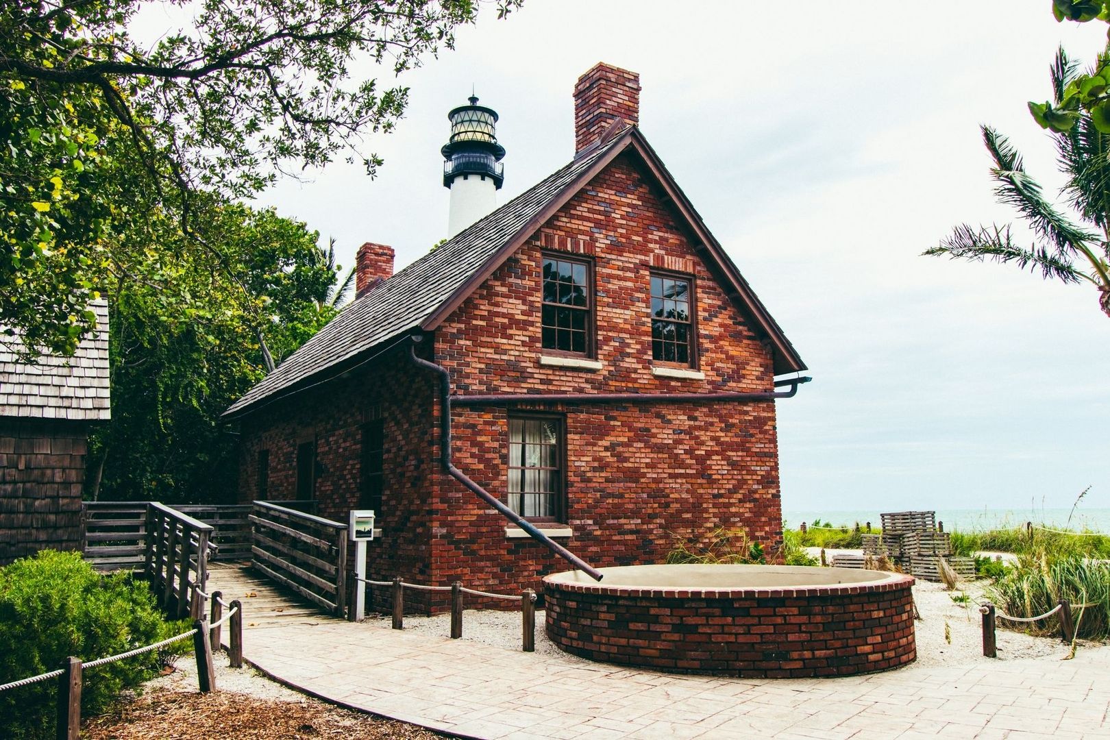 Historic brick lighthouse keeper’s building beside a tropical shoreline
